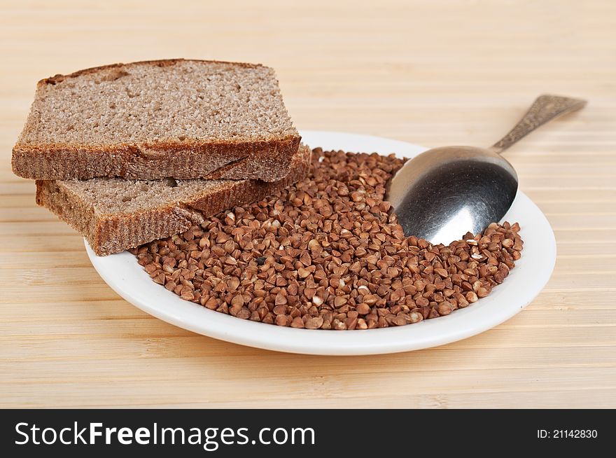 Buckwheat and rye bread on plate on a wooden background