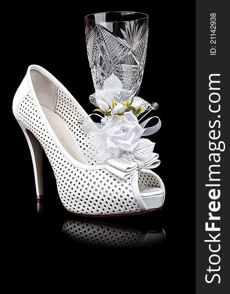 Crystal goblet and wedding shoe isolated on a black background