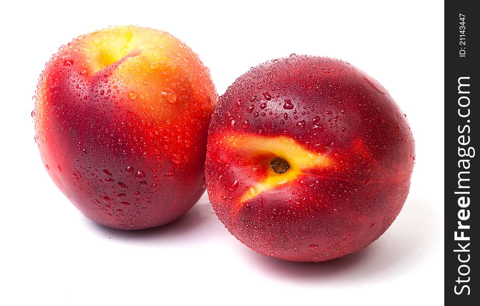 Two fresh nectarines with water drops isolated on white background