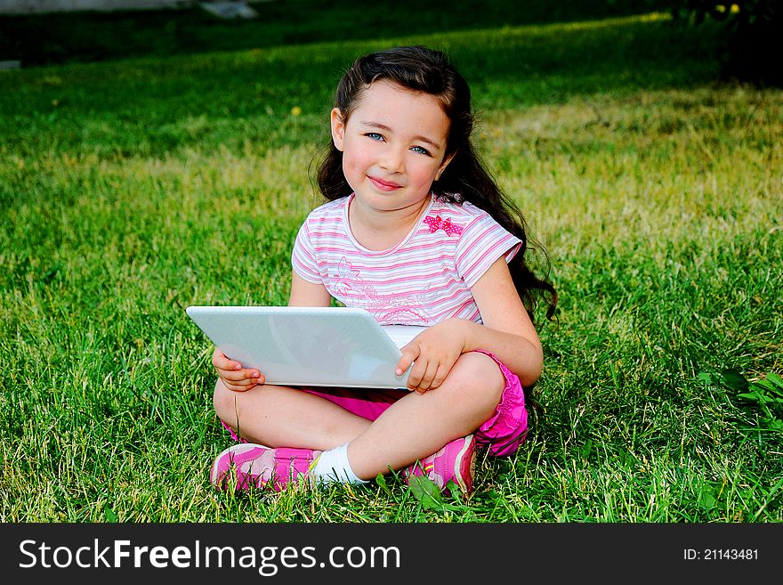 The small nice girl with the laptop on walk in park. The small nice girl with the laptop on walk in park