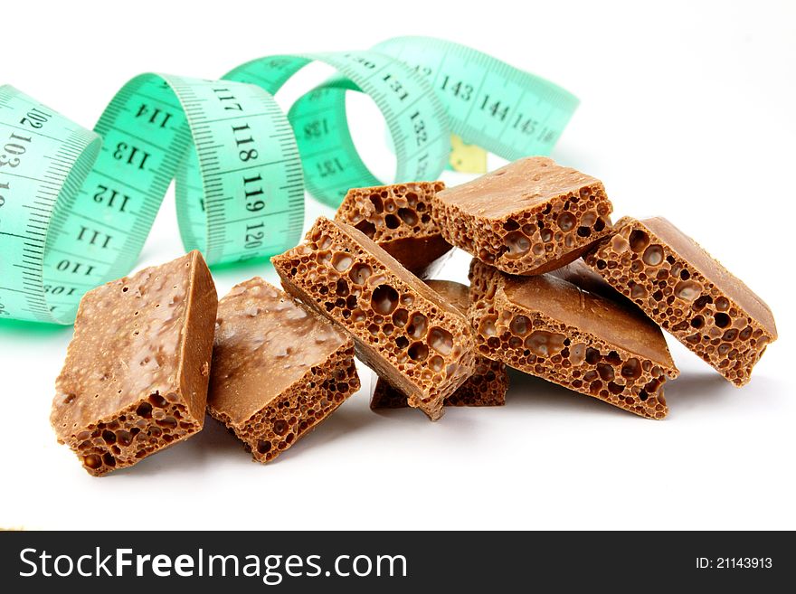 Broken chocolate bar and measuring tape on white background. Broken chocolate bar and measuring tape on white background