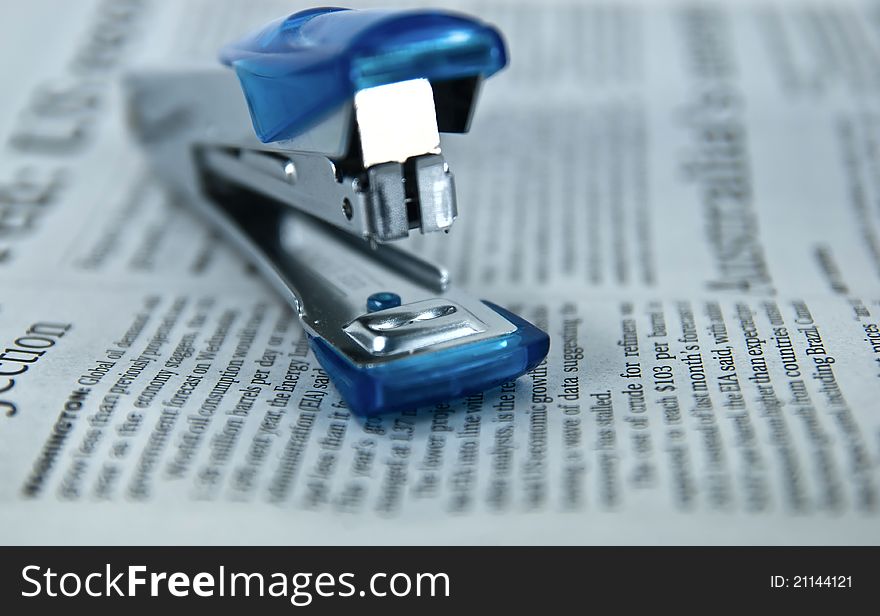Simple small stapler is located on surface of Newspaper. Simple small stapler is located on surface of Newspaper.