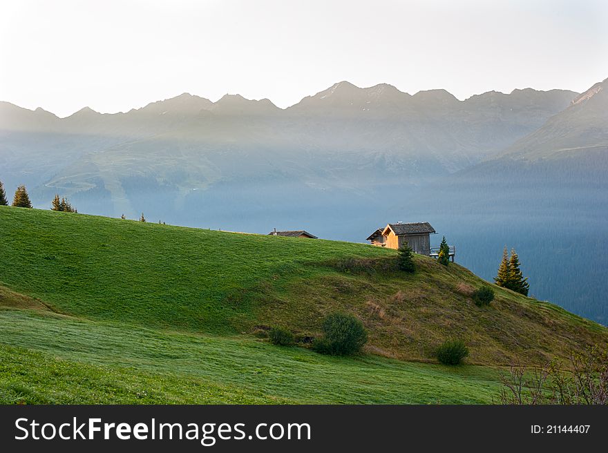 Early dawn in the mountains of Austria against the backdrop of meadows, mountains and alm