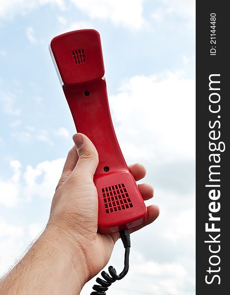Man holding a red phone at the sky background