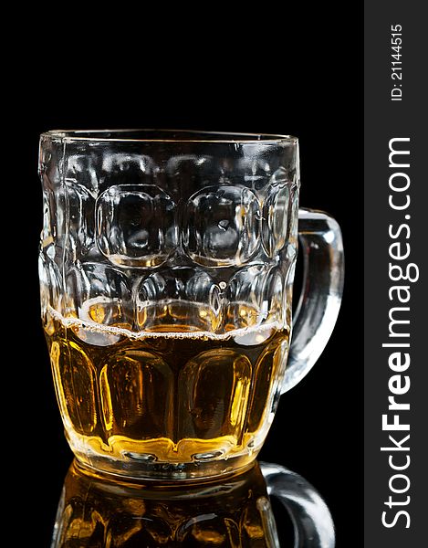 Half-full glass of beer isolated on a black background
