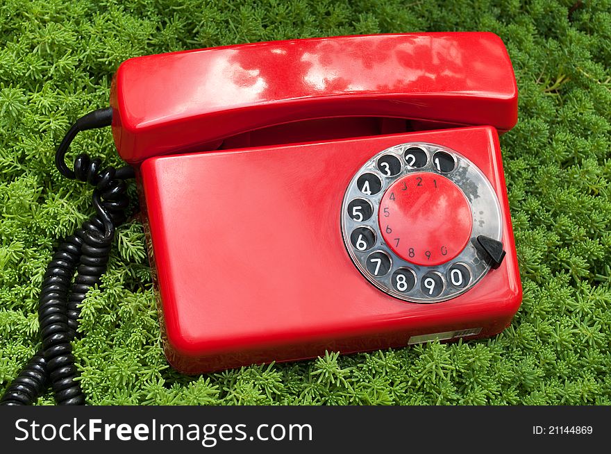 Red and old telephone on a green grass background. Red and old telephone on a green grass background
