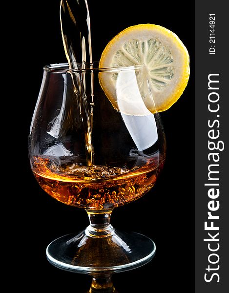 Cognac with lemon in a classic glass isolated on a black background