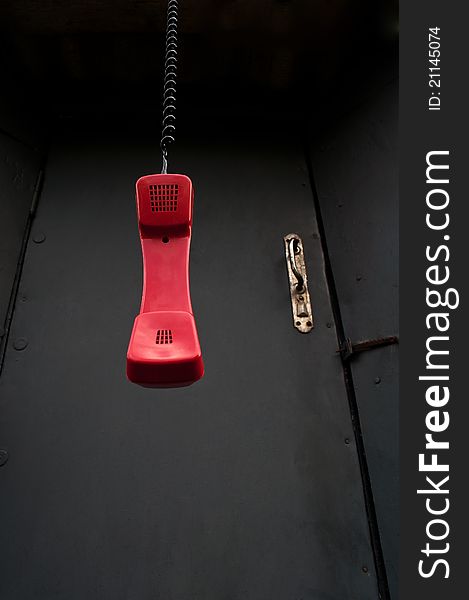 Handset hangs against the black of the old doors background. Handset hangs against the black of the old doors background