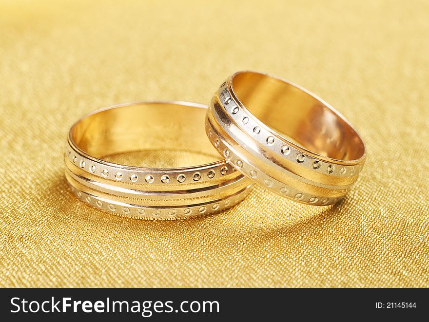 Gold wedding rings lying on silk