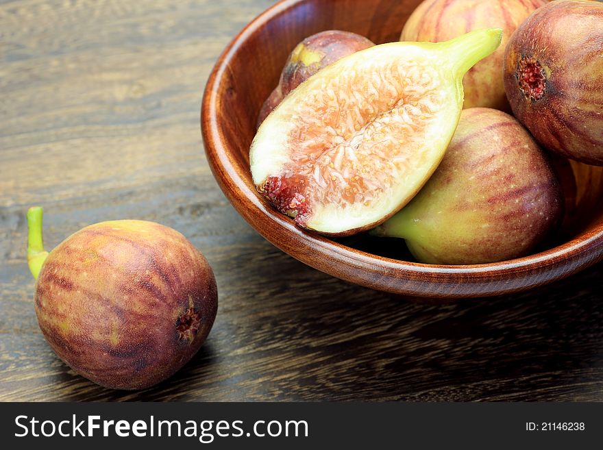 I put several figs in wooden tableware and I took it at a dining table.