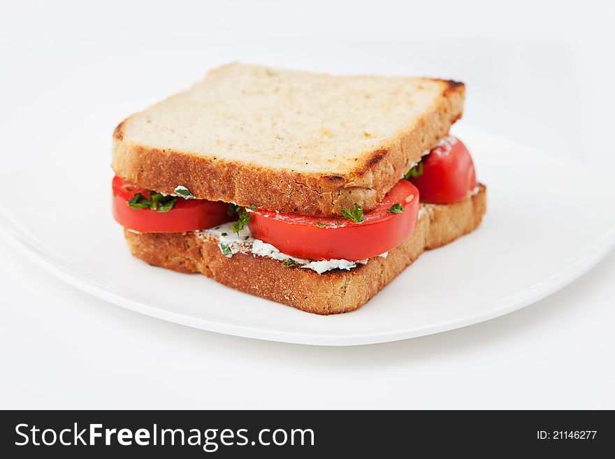 Sandwich with tomatoes and salty cheese on white plate. Sandwich with tomatoes and salty cheese on white plate