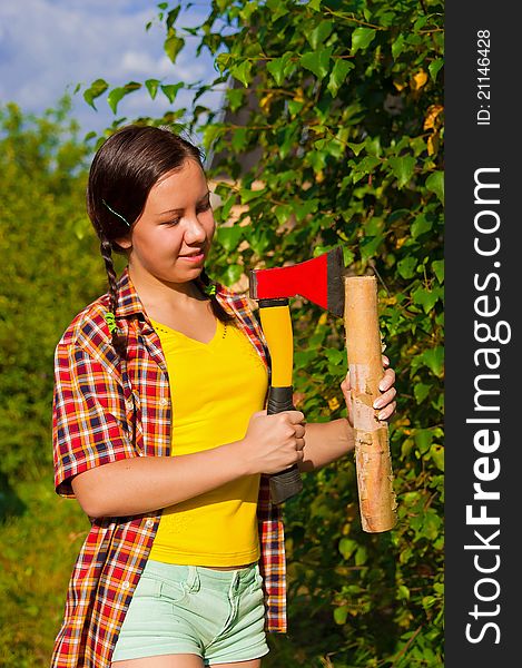 Young woman holding an axe and chock in the forest