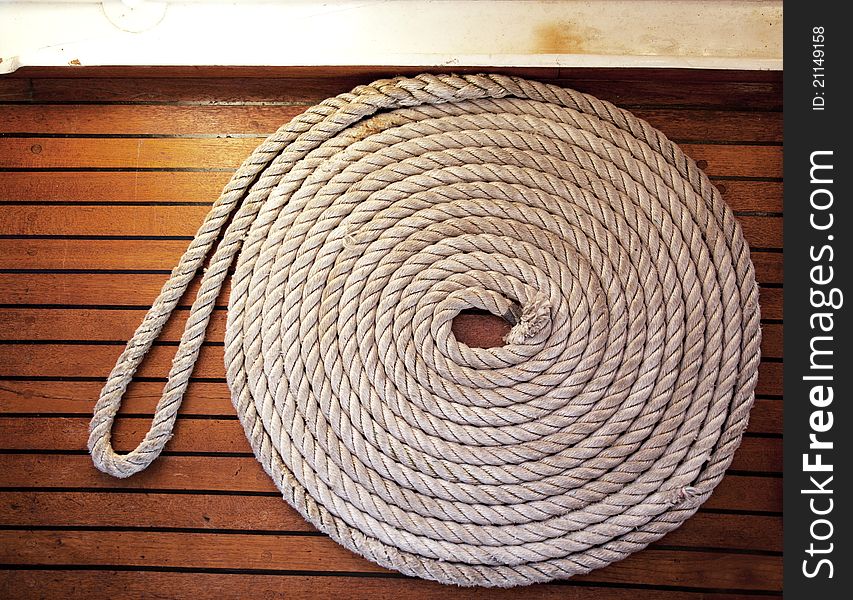 A rope coil laid across teak decking. A rope coil laid across teak decking