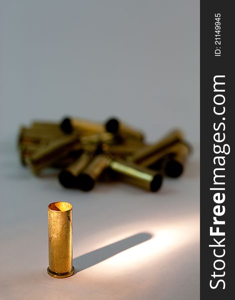 A group of emply .38 caliber brass shell casings with focus and spotlight on the front one. A group of emply .38 caliber brass shell casings with focus and spotlight on the front one.
