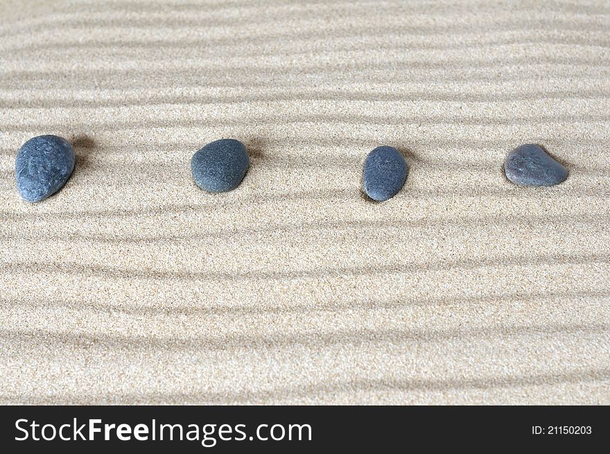 Four stones on background of sand
