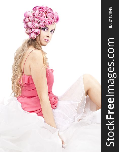 Young beautiful woman with pink flowers on her head and in pink dress over white