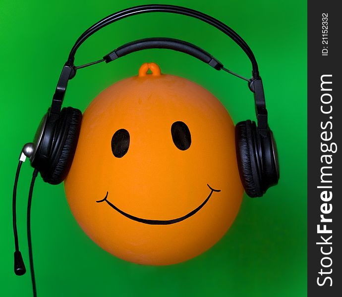 Inflatable orange ball Dj in earphone on green background