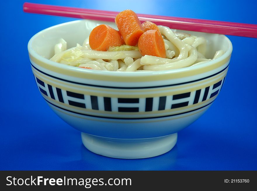 A bowl of noodle soup with pink chopsticks