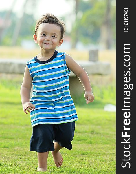 Active young boy smiling and running in the park