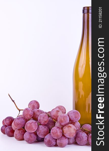 Red fresh grapes with bottle on white background