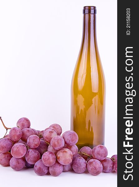 Red fresh grapes with bottle on white background