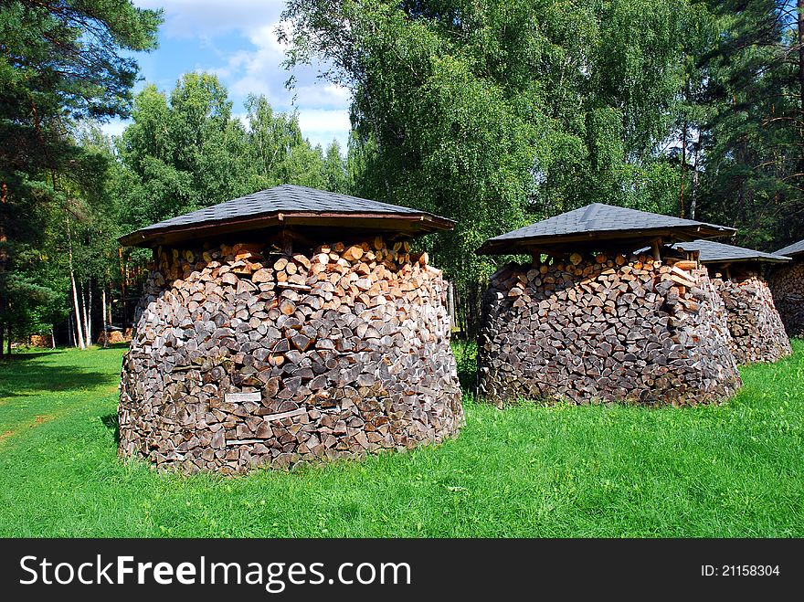 A photo of three piles of wood on the green grass