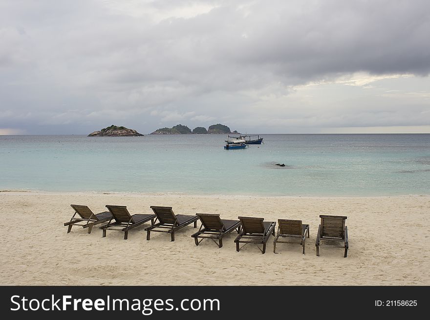 Empty beach chairs facing quiet sea under cloudy sky, Redang Island, Malaysia. Empty beach chairs facing quiet sea under cloudy sky, Redang Island, Malaysia