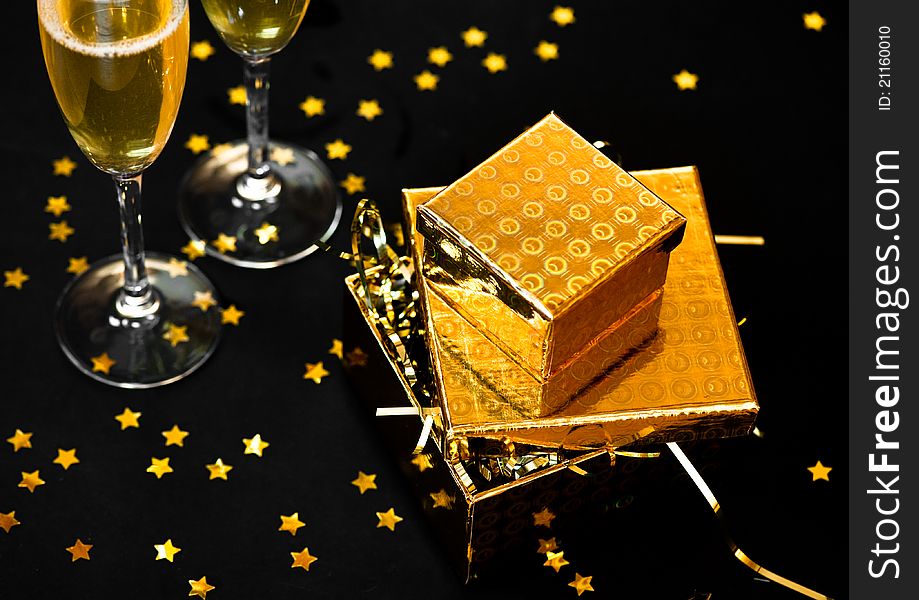 Two glasses of champagne with golden gift boxes