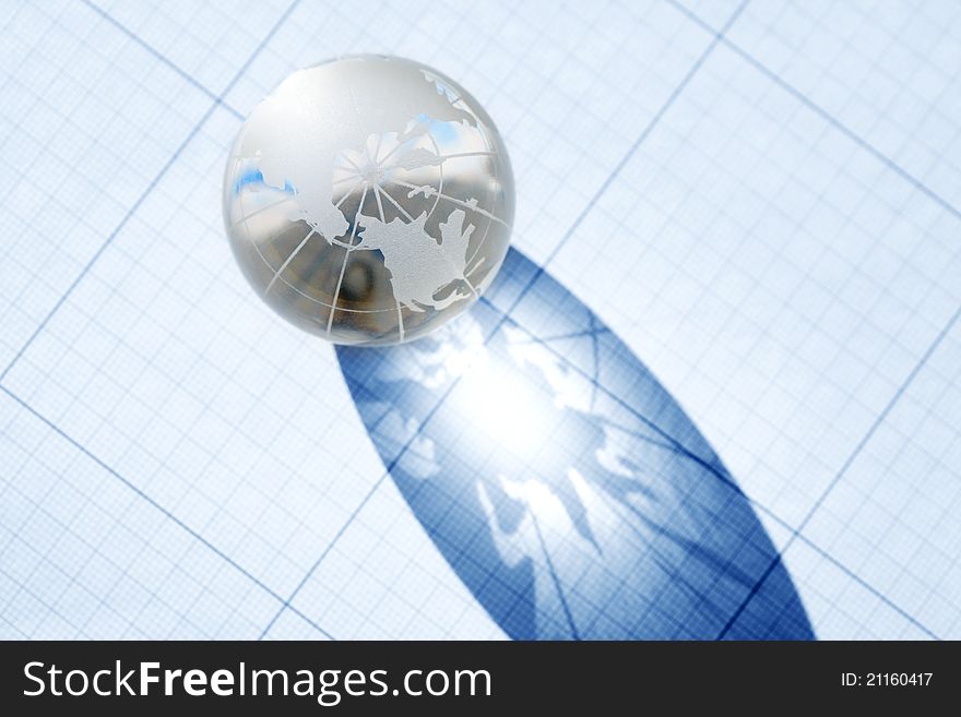 Business concept. Glass globe with long shadow on graph paper background