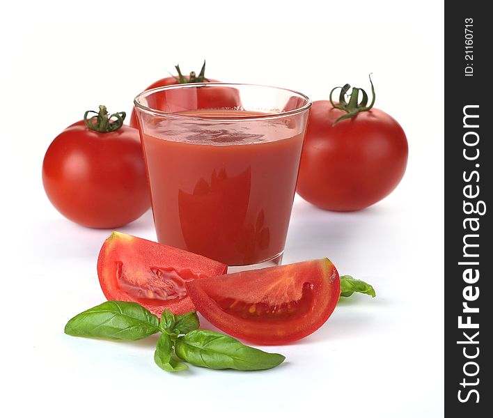 Glass of tomato juice and fruits with green leaves isolated on white