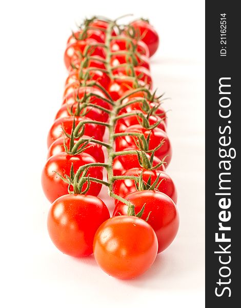 Branch of red cherry tomatoes on a white background