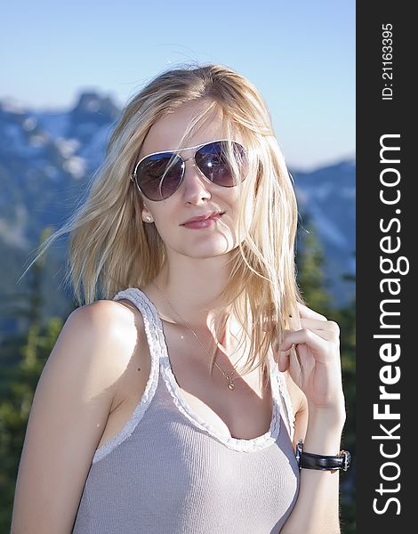 Close-up portrait of beautiful young blonde girl in the park and mountains on a background. Close-up portrait of beautiful young blonde girl in the park and mountains on a background