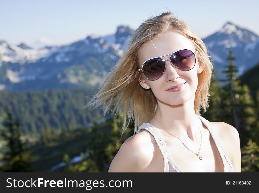 Close-up portrait of beautiful young blonde girl in the park and mountains on a background. Close-up portrait of beautiful young blonde girl in the park and mountains on a background