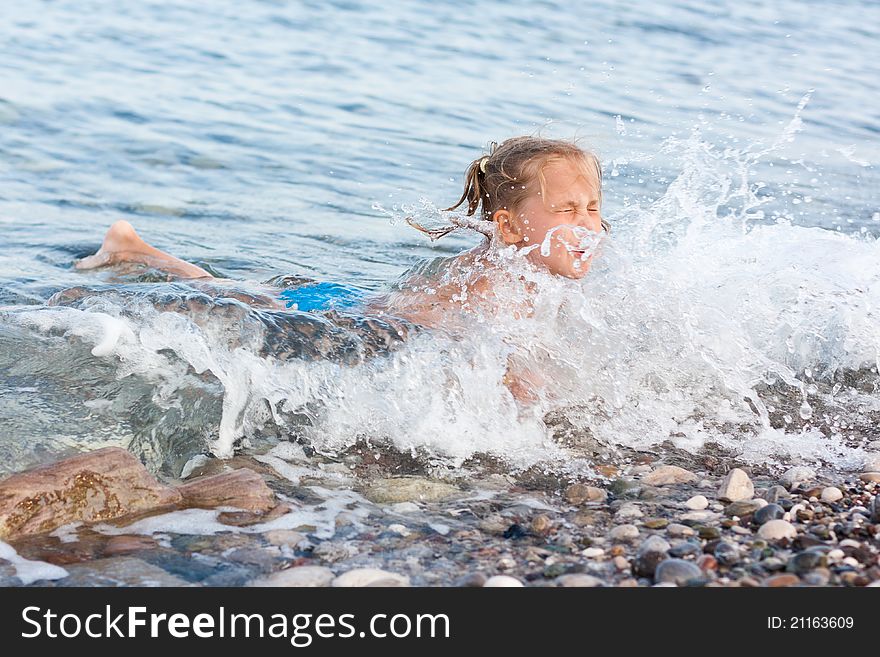 Beautiful girl lying at the seashore in waves and splashes