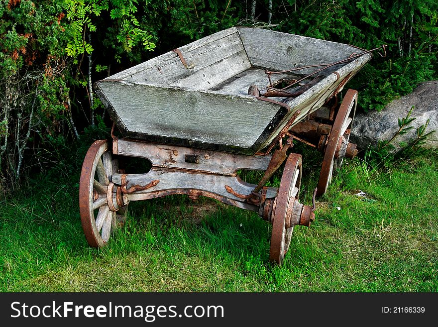 Old and used wagon standing near bushes
