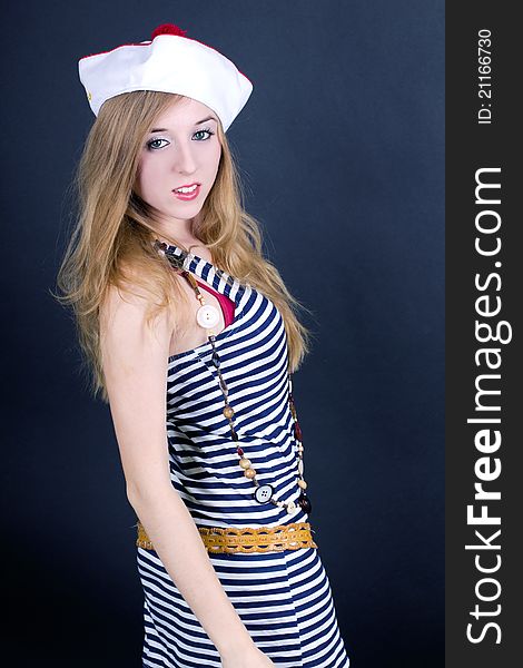 Young attractive woman wearing sailor dress and hat in studio. Young attractive woman wearing sailor dress and hat in studio