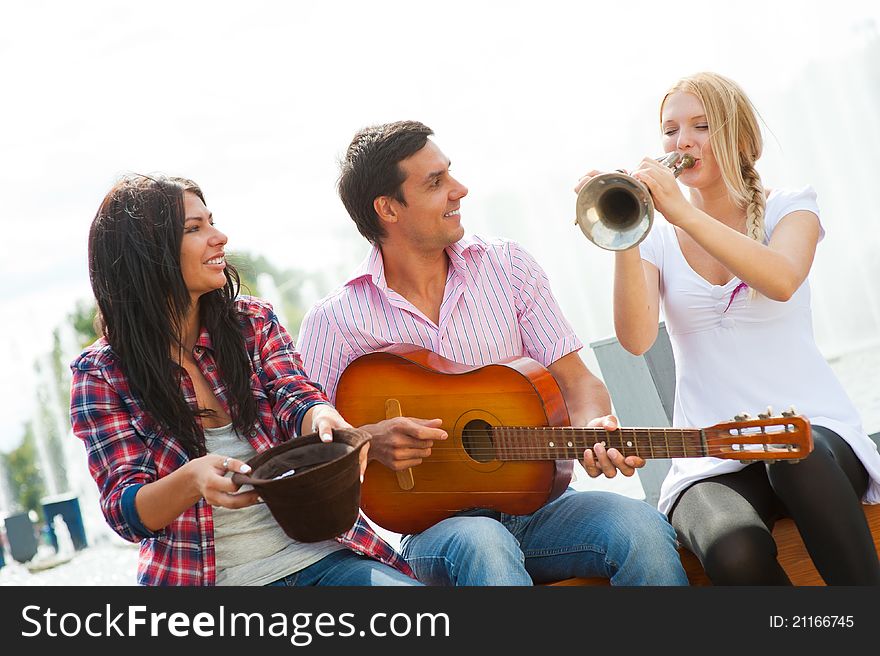 Young friends play the guitar and trumpet in the park