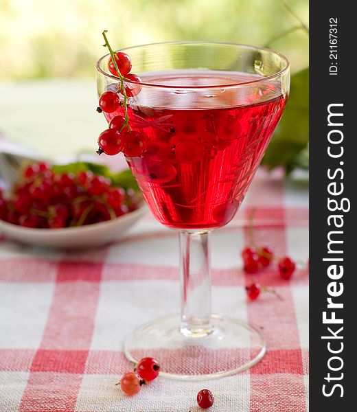 Red currant wine in glass on natural background. Selective focus