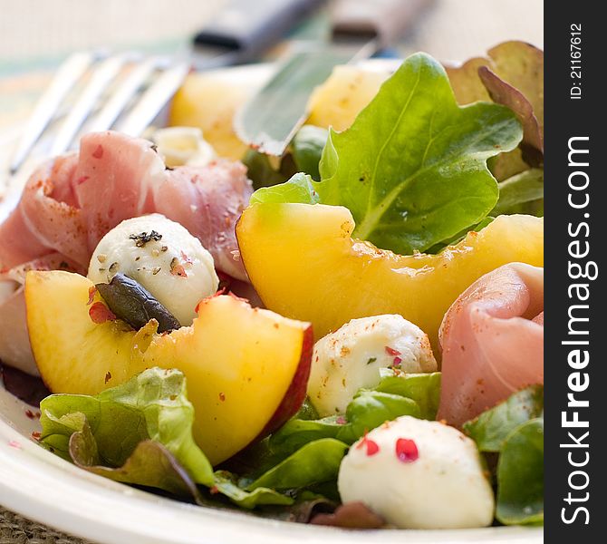 Fresh salad with peach, mozzarella cheese and ham. Selective focus