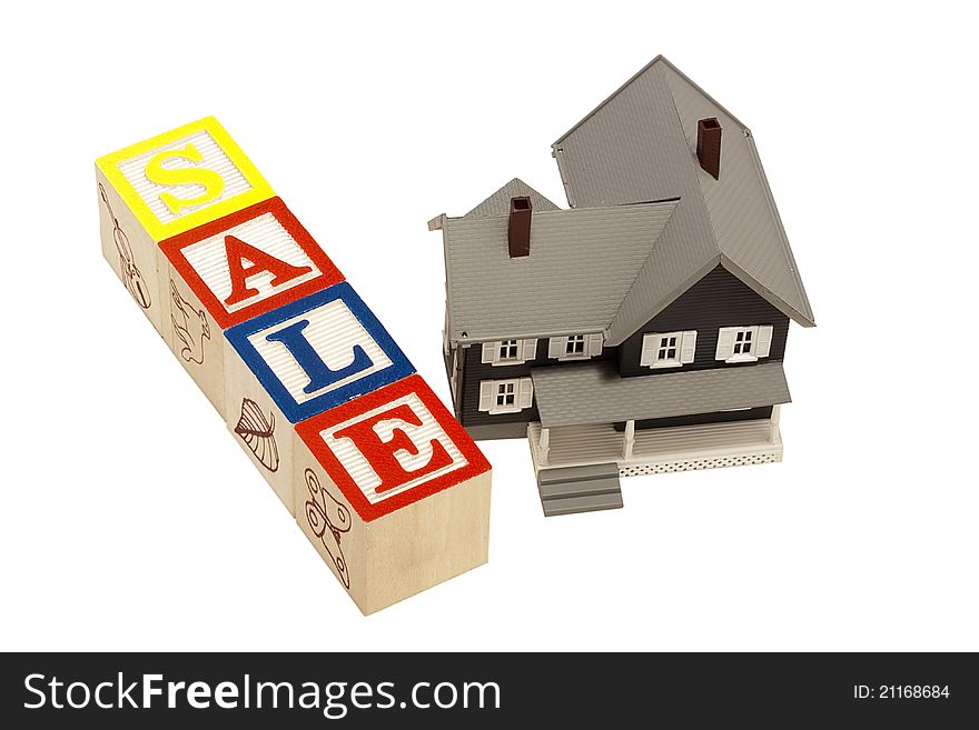 House model next to blocks spelling out the word sale. House model next to blocks spelling out the word sale.