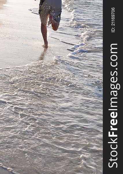 Feet and legs of man running on beach in golden afternoon light. Caribbean Sea, Cuba. Feet and legs of man running on beach in golden afternoon light. Caribbean Sea, Cuba