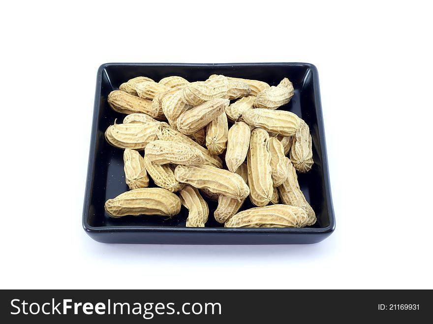 Peanut on black plate isolated on white background.