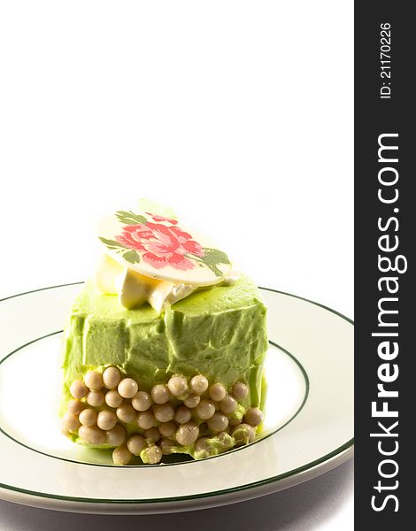 A piece of green cake with whipped cream and sugar on white background