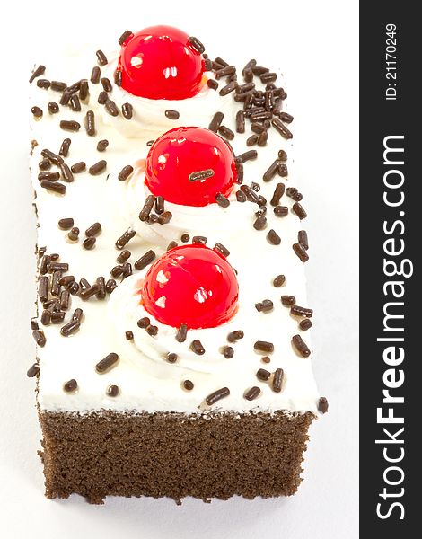 A piece of chocolate cake garnished with cherries and chocolate chips