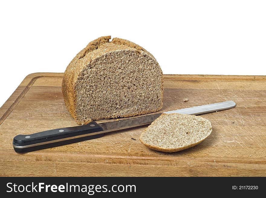A home baked wholemeal loaf with bread knife and cutting board. Isolated on white background with path. A home baked wholemeal loaf with bread knife and cutting board. Isolated on white background with path.