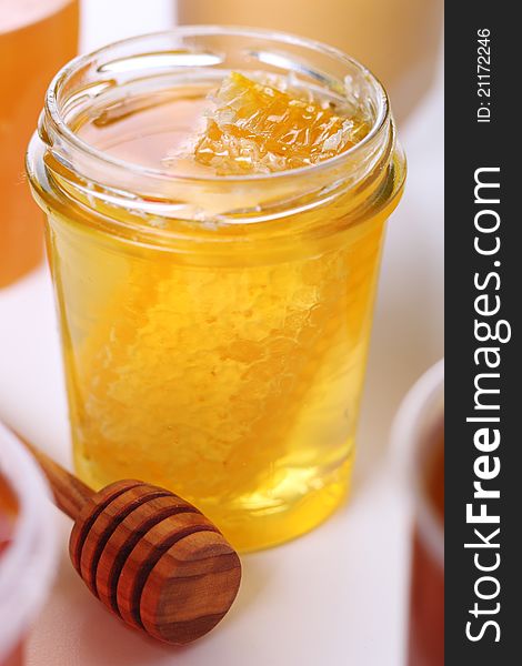 Jar of honey with honeycomb and wooden stick