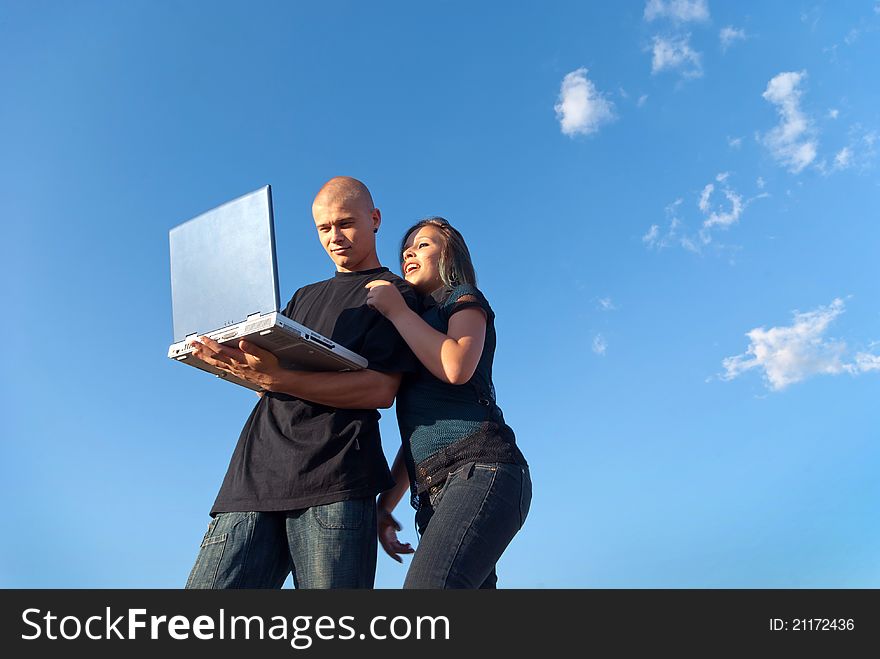 A young men working with laptop and smiling girl in the background sky with clouds. A young men working with laptop and smiling girl in the background sky with clouds
