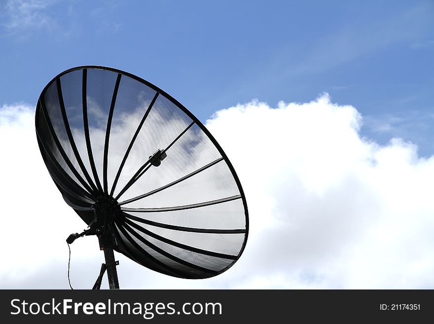 Black satellite dish antenna on blue sky background