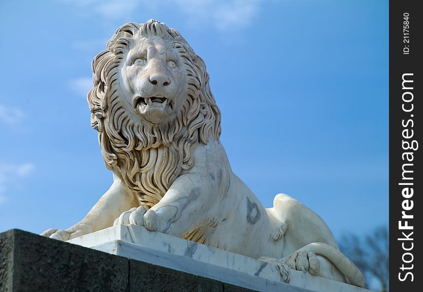 The sculpture marble lion on blue sky background. The sculpture marble lion on blue sky background