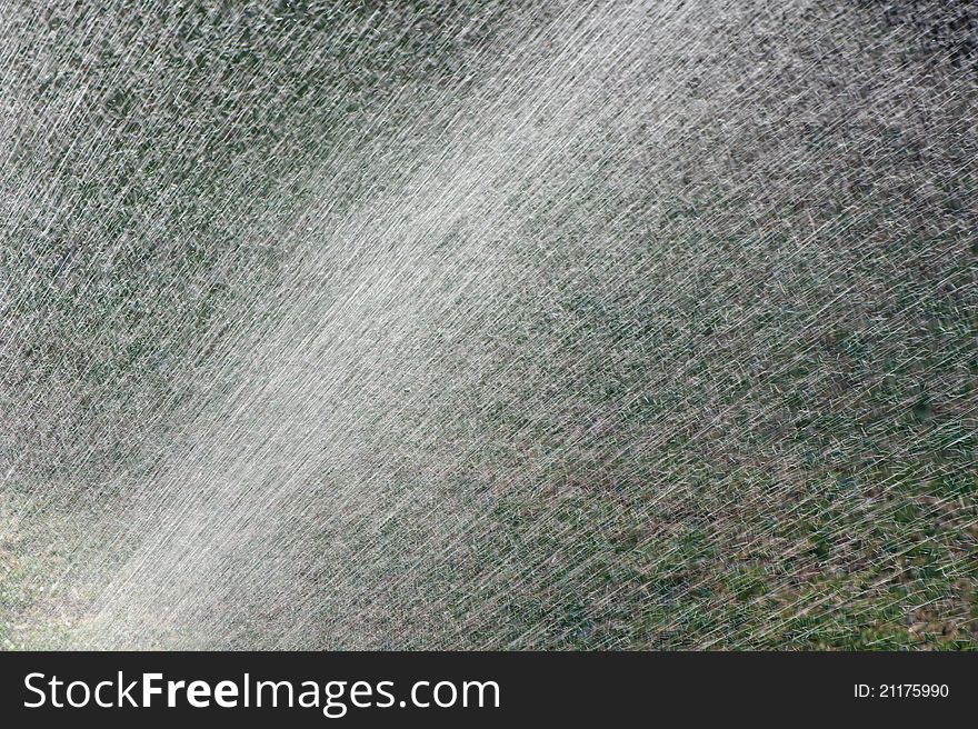 Water from an irrigation sprinkler head shooting droplets of water into the sunlight. Will make a good mobile phone or desktop background or abstract frame. Water from an irrigation sprinkler head shooting droplets of water into the sunlight. Will make a good mobile phone or desktop background or abstract frame.